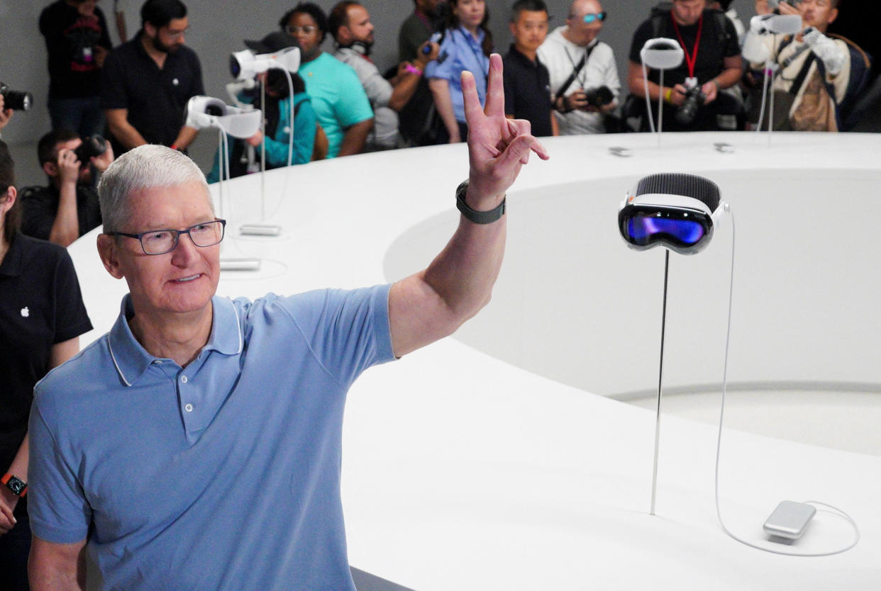 Apple CEO Tim Cook gestures next to Apple's Vision Pro headsets at Apple's annual Worldwide Developers Conference at the company's headquarters in Cupertino, California, U.S. June 5, 2023. REUTERS/Loren Elliott