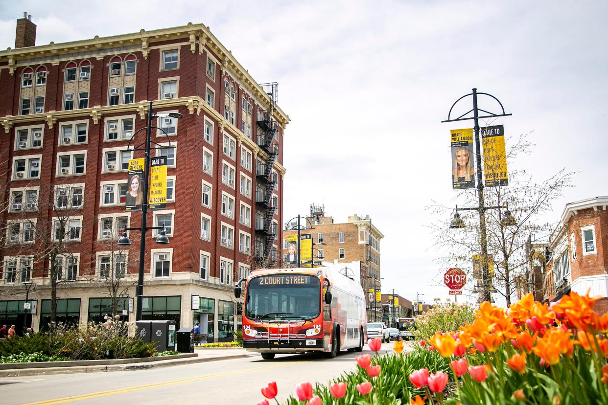 An Iowa City Transit Proterra ZX5 electric bus drives along its route on E. Washington Street past a planter with tulips in full bloom, Wednesday, May 4, 2022, in Iowa City, Iowa.