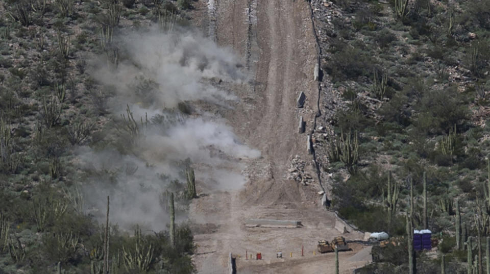 Construction crew perform a controlled detonation at the base of Monument Hill in Organ Pipe Cactus National Monument west of Lukeville, Ariz., on Wednesday, Feb. 26, 2020. Construction crews in southern Arizona have recently began blasting hills at the site to clear space for a new border wall system, bulldozing through a place called Monument Hill to construct a 30-foot (9-meter) steel wall along the U.S.-Mexico border. (Josh Galemore/Arizona Daily Star via AP)