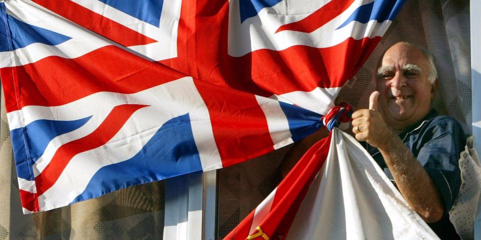 A Gibraltarian gives the thumbs up from his balcony which is adorned with Gibraltarian and Union flags in the British colony of Gibraltar November 6, 2002. [Gibraltar chief minister Peter Caruana predicts the colony's people will overwhelmingly reject the idea of Spain and Britain sharing sovereignty over the rock in a referendum scheduled for November 7