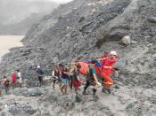 In this photo released from Myanmar Fire Service Department, rescuers carry a recovered body of a victim of a landslide from a jade mining area in Hpakant, Kachine state, northern Myanmar Thursday, July 2, 2020. Myanmar government says a landslide at a jade mine has killed dozens of people (Myanmar Fire Service Department via AP)