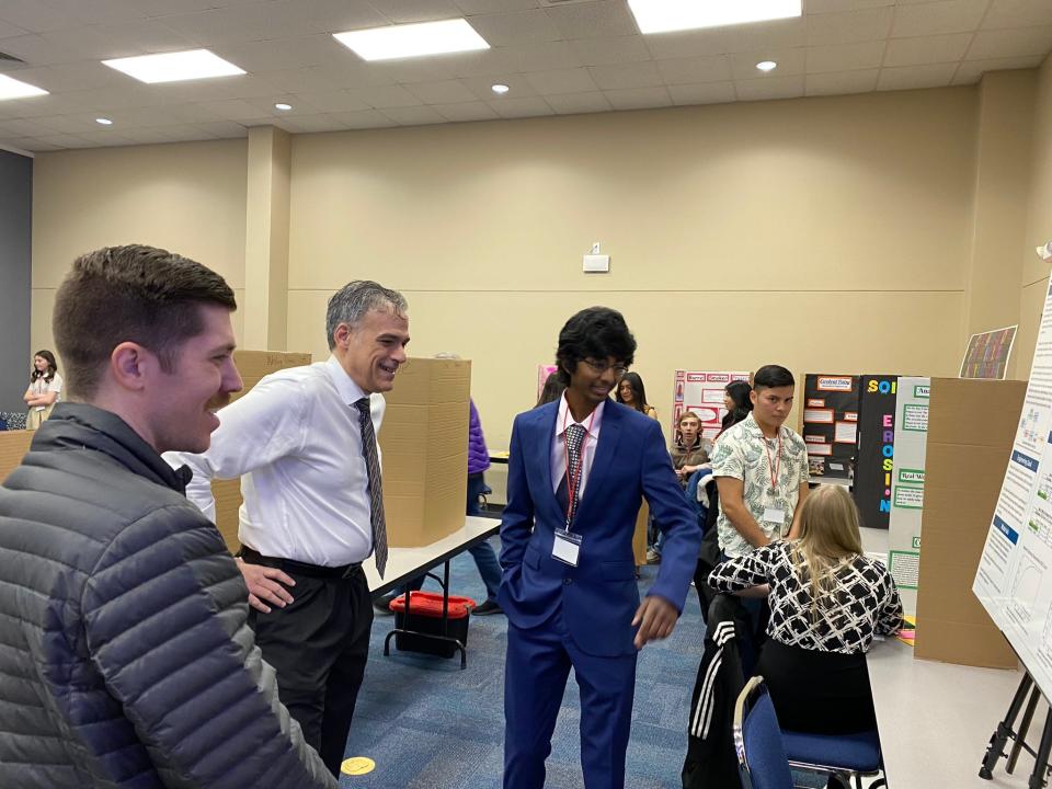 Dr. Rigoberto Hernandez, center, views Rider High School student Sai Chada's project, which was the top winner at the regional science fair in 2023. On left is teacher Bryce Henderson.