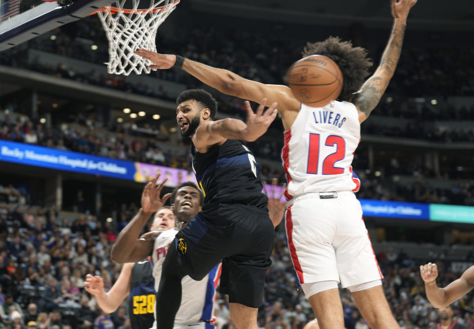 Denver Nuggets guard Jamal Murray, front left, passes the ball behind Detroit Pistons forward Isaiah Livers (12) in the first half of an NBA basketball game Sunday, Jan. 7, 2024, in Denver. (AP Photo/David Zalubowski)