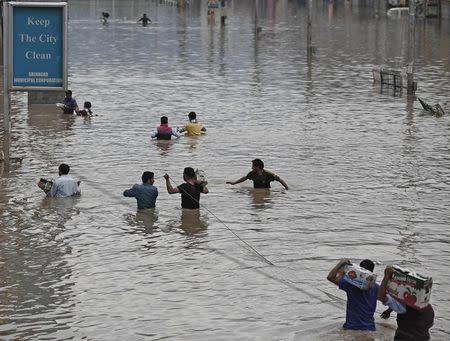 Local residents wade through a flooded street to deliver relief material to the stranded victims in Srinagar September 12, 2014. REUTERS/Adnan Abidi