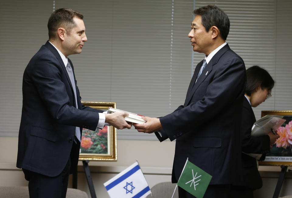 Israeli Embassy representative Peleg Lewi, left, hands Anne Frank-related books to Suginami Ward Mayor Ryo Tanaka at the Suginami Ward Office in Tokyo Thursday, Feb. 27, 2014. The Israeli Embassy is donating 300 books to Tokyo public libraries after the recent vandalism of a similar number of such books in their collections. More than 300 books related to Anne Frank, including copies of "The Dairy of a Young Girl," have been found damaged in Tokyo libraries. Suginami was particularly hard hit with 121 books vandalized. (AP Photo/Shizuo Kambayashi)