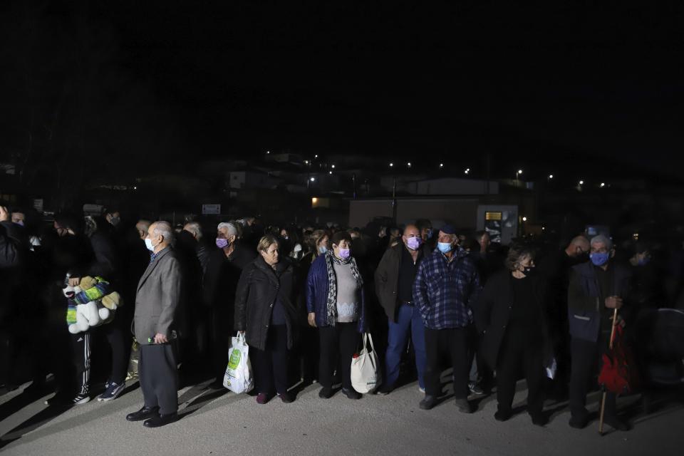 Local residents wait for a bus which will transfer them to hotels after an earthquake in Damasi village, central Greece, Wednesday, March 3, 2021. An earthquake with a preliminary magnitude of at least 6.0 struck central Greece Wednesday and was also felt in neighboring Albania and North Macedonia, and as far as Kosovo and Montenegro. (AP Photo/Vaggelis Kousioras)