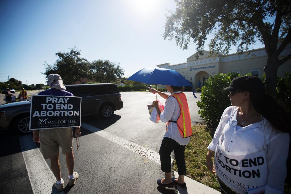 People protesting abortion offer literature to an exiting vehicle at Planned Parenthood in Fort Myers on Thursday, October 15, 2020. 