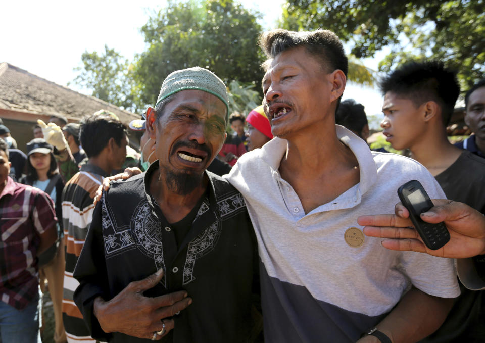 In this Tuesday, Aug. 7, 2018, photo relatives react as rescue teams recover the bodies of victims killed in an earthquake in North Lombok, Indonesia, Tuesday, Aug. 7, 2018. (AP Photo/Tatan Syuflana)