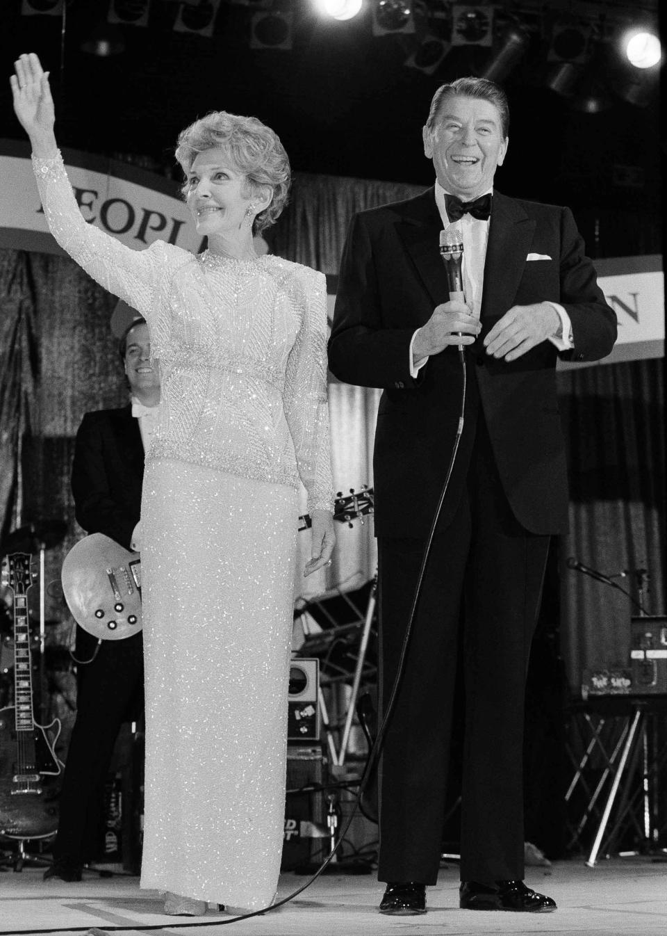 President Ronald Reagan smiles as first lady Nancy Reagan waves to guests at the Ball for Young Americans at the D.C. Armory in Washington, Jan. 21, 1985. President Reagan re-enacted his oath of office earlier in the day in the rotunda of the Capitol. (AP Photo/Ira Schwarz)