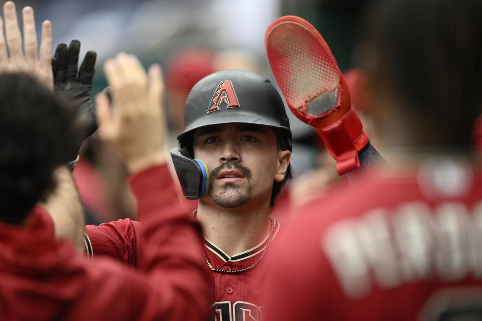 Arizona Diamondbacks' Corbin Carroll high-fives in the dugout after he scored on a sacrifice fly by Emmanuel Rivera during the fourth inning of a baseball game against the Washington Nationals, Thursday, June 22, 2023, in Washington. (AP Photo/Nick Wass)