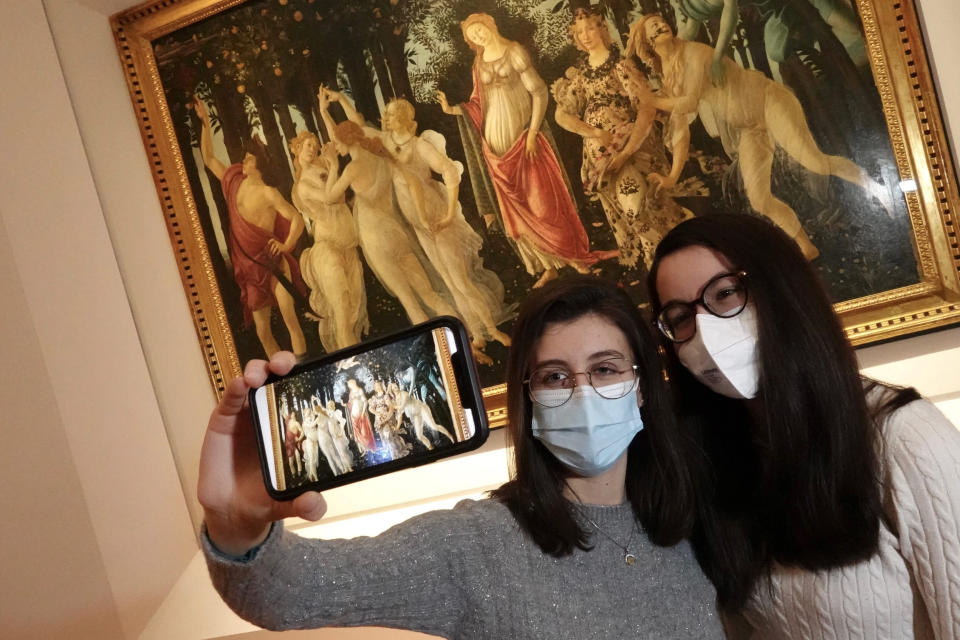 Dos visitantes con cubrebocas se toman una selfie frente a la obra del s XV de Sandro Botticelli “Primavera” en el museo Galería Uffizi que reabrió tras meses cerrado por la pandemia de COVID-19 en Florencia, Italia, el jueves 21 de enero de 2021. (Foto Pietro Masini/LaPresse via AP)