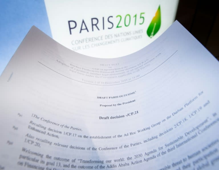 An illustration picture taken on December 10, 2015 in Paris shows a draft for the outcome of the COP21 United Nations conference on climate change next to the logo of the summit