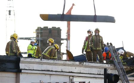 Rescue workers lift a rotor blade from the site of a police helicopter crash on to the Clutha Pub in central Glasgow, Scotland, December 1, 2013. REUTERS/Andrew Winning