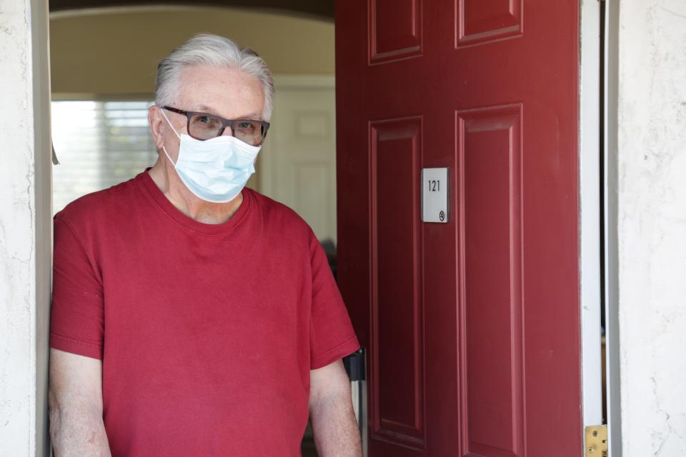 In this 2020 file photo from the Desert Sun, Lee Fournier stands in the entryway of his hotel room provided by Project Roomkey at Rodeway Inn & Suites in Indio, Calif. Project Roomkey was an effort by the state to house individuals experiencing homelessness during the COVID-19 pandemic.