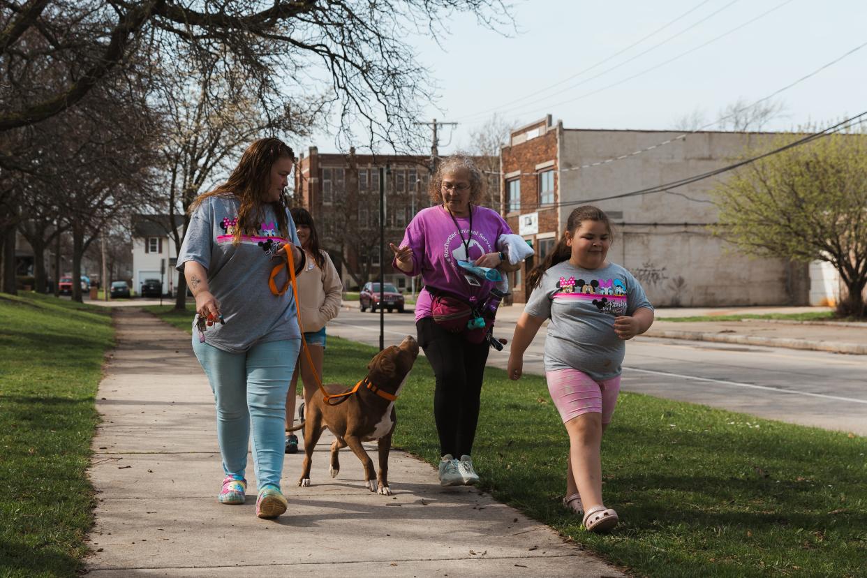 (Left to right) Deanna Viera, Elissa Lopez and Elicia Lopez accompany Luna, a prospective foster dog, on a walk as Rochester Animal Services volunteer Ann Marie Switzer hands the brown-haired, mixed breed treats on Wednesday, April 10, 2024.