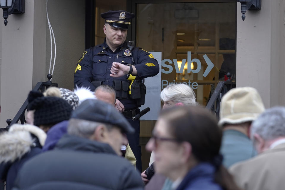 Oficial de policía de Wellesley, Massachusetts, en una sucursal de Silicon Valley Bank, el lunes 13 de marzo de 2023, mientras los clientes esperan la apertura. Foto AP /Steven Senne