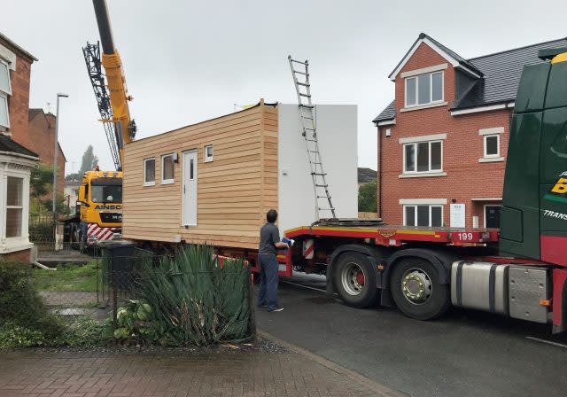 A micro-home is lifted off the back of a lorry