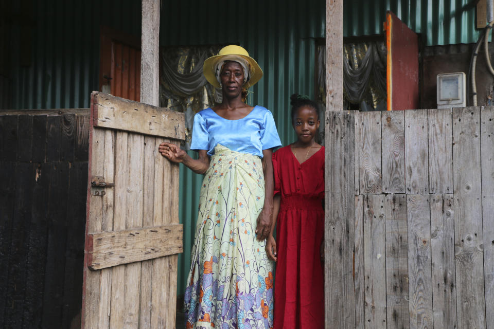 Zenabou S, a Comoros woman married to a French man in Mayotte and her French daughter, stand at their door step as they prepare to move, in the Talus 2 district of Koungou, in the French Indian Ocean territory of Mayotte Saturday, April 22, 2023. France is facing a migration quagmire on the island territory of Mayotte off Africa’s east coast. The government sent in 2,000 troops and police to carry out mass expulsions, destroy slums and eradicate violent gangs. But the operation has become bogged down and raised concerns of abuse, aggravating tensions between local residents and immigrants from the neighboring country of Comoros. (AP Photo/Gregoire Merot)