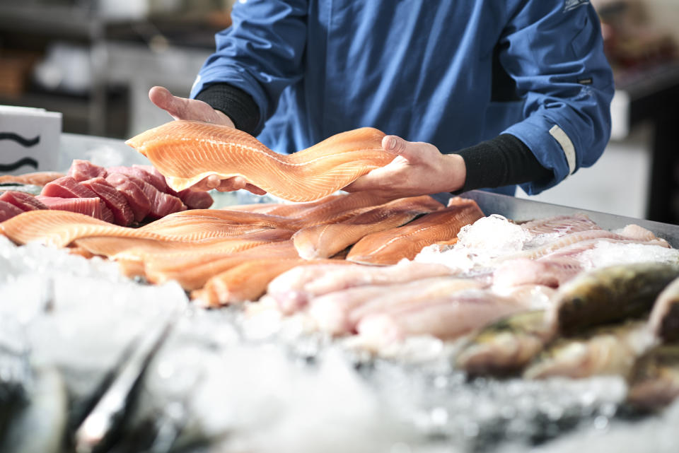 Fischverkäufer nimmt Fisch-Filet aus der Kühlung.