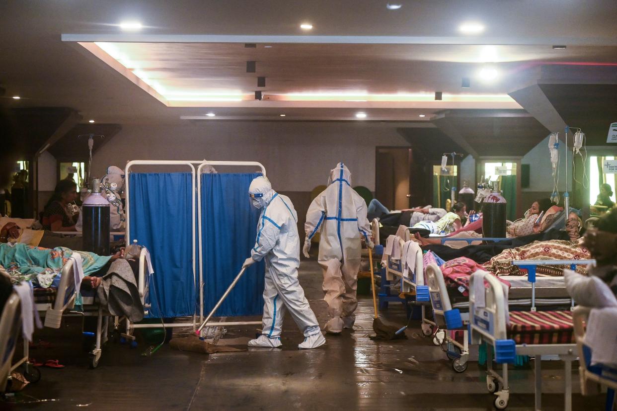 TOPSHOT - A health worker wearing a personal protective equipment (PPE) suit cleans the floor inside a banquet hall temporarily converted into a Covid-19 coronavirus ward in New Delhi on May 1, 2021. (Photo by Prakash SINGH / AFP) (Photo by PRAKASH SINGH/AFP via Getty Images)