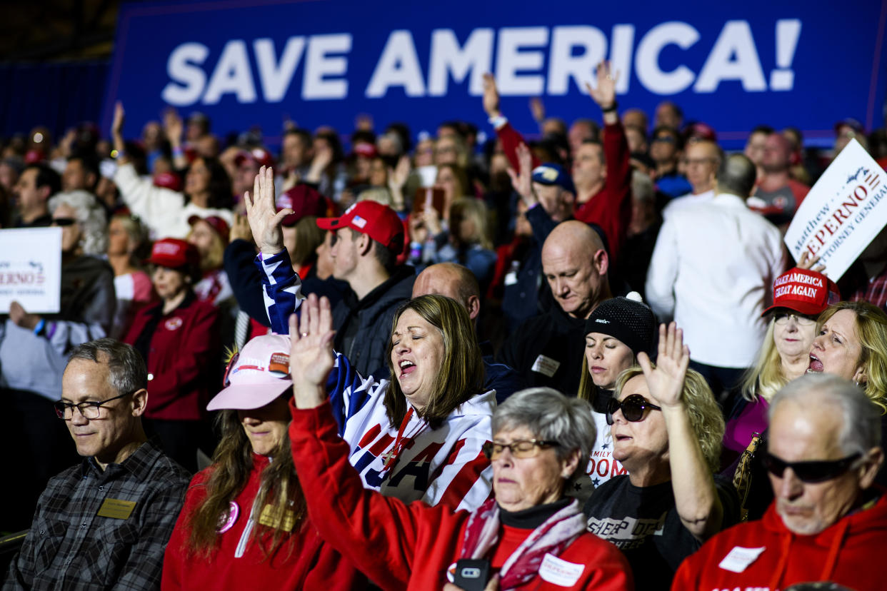 Asistentes rezan en un mitin similar a uno de campaña del expresidente Donald Trump en Washington, Míchigan, el 2 de abril de 2022. (Brittany Greeson/The New York Times)