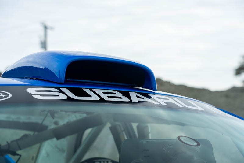 close-up shot of the roof of a blue subaru 2.5rs. the car has subaru written across the top of the windshield, with a large rally-style scoop on the roof meant to draw fresh air into the cabin
