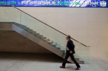 A man walks under an electronic information board at the London Stock Exchange in the City of London January 2, 2013. REUTERS/Paul Hackett