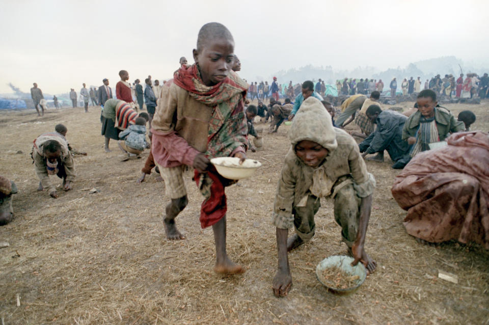 FILE - Rwandan refugee children scramble for loose beans at a food distribution center in the Kibumbu refugee camp near Goma, Zaire, now Congo, Aug. 13, 1994. (AP Photo/Santiago Lyon, File)