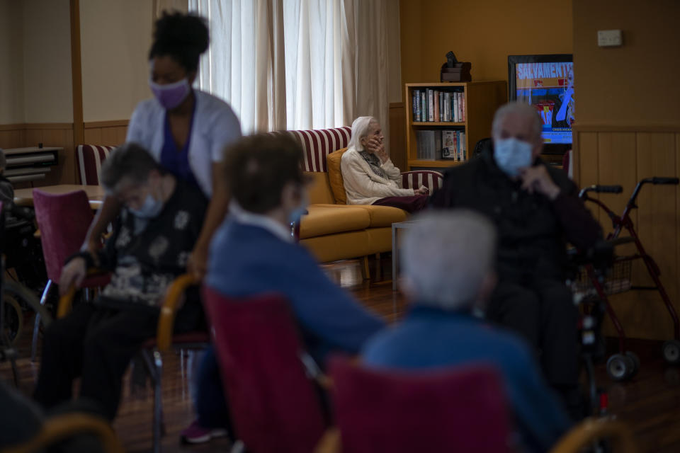 Residents sit in a living room and watch TV at the Icaria nursing home in Barcelona, Spain, Friday, Nov. 27, 2020. The surge in Europe is happening despite the retaining wall of measures erected since the spring, including facilities tailored only for residents with the coronavirus. It’s also pitching authorities and elder care professionals in a race against the clock before mass vaccinations can begin. (AP Photo/Emilio Morenatti)