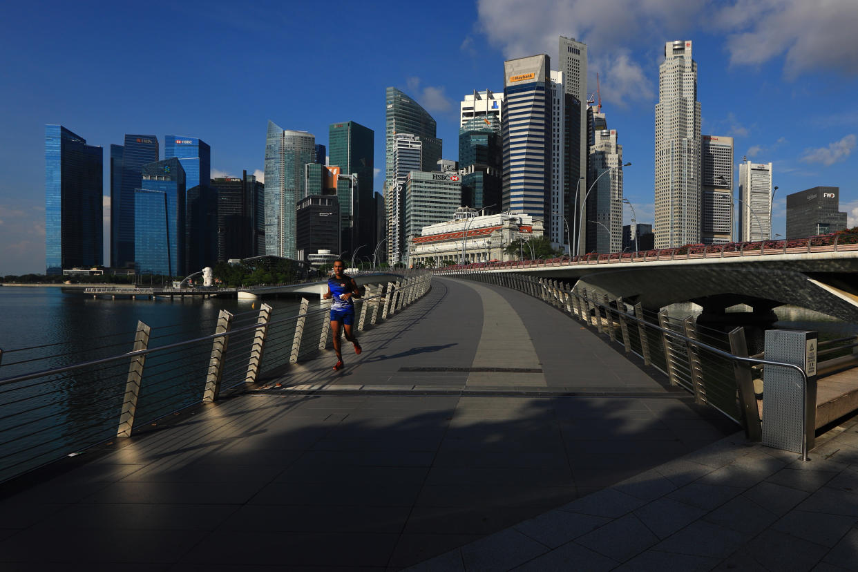 SINGAPORE - MAY 26:  A man jogs along the Jubilee Bridge with the central business district pictured in the background on May 26, 2020 in Singapore. Singapore is set to ease the partial lockdown measures against the coronavirus (COVID-19) pandemic after 1 June in three phases to resume activities safely after it sees a decline in the new infection cases in the community. Singapore's gross domestic product (GDP) is expected to shrink as much as 7 percent this year as the country battles the slump in global trade and travel amid the coronavirus pandemic, according to the government report in the local media today.  (Photo by Suhaimi Abdullah/Getty Images)