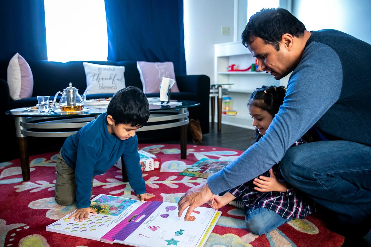 Hamayoon Azizi looks at a workbook with his children at their home in Iowa City.