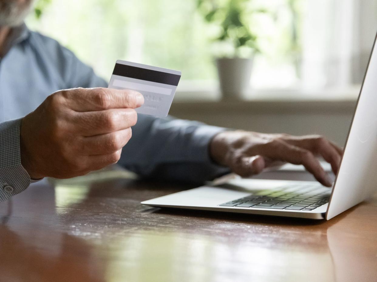 A stock image shows an older man making a payment online using his credit card.