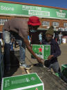 Workers load up purchased alcohol beverages outside the Sam Liquor Store in Thokoza township, near Johannesburg, South Africa, Monday, June 1, 2020. Liquor stores have reopened Monday after being closed for over two months under lockdown restrictions in a bid to prevent the spread of coronavirus.(AP Photo/Themba Hadebe)