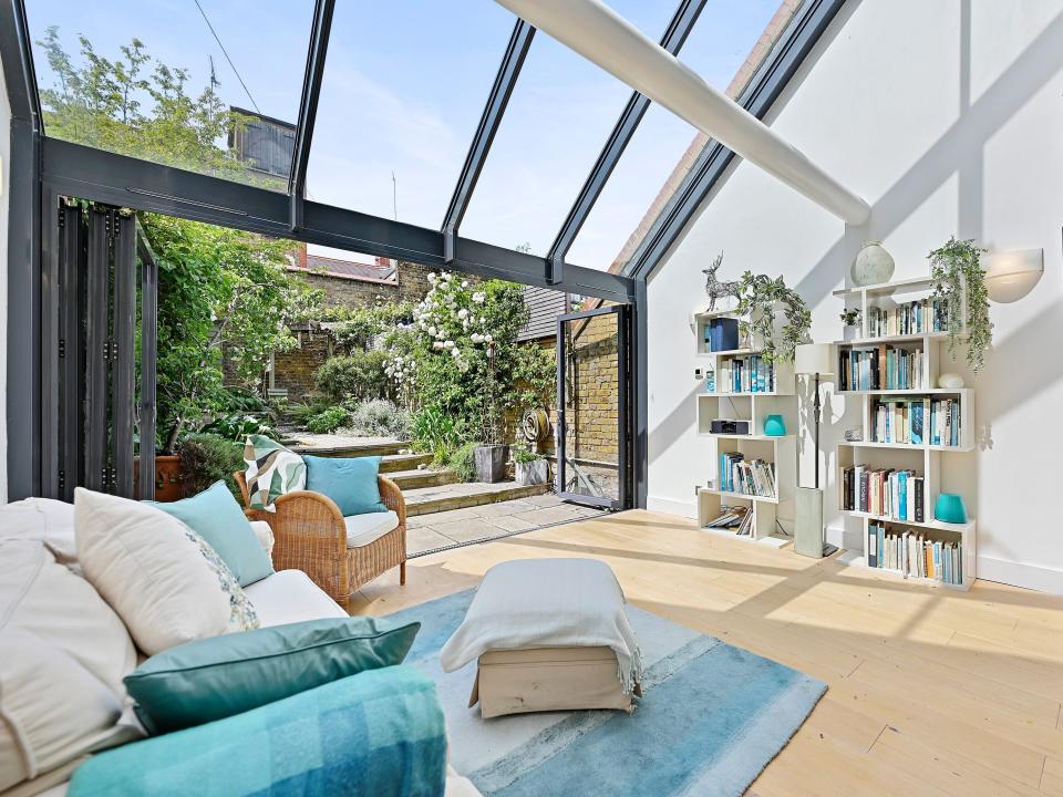 Inside a room with white walls, a wood floor, and an outdoor area in the back with large windows.