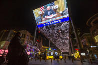 A vendor selling lighted balloons stands near a large video showing a government news report about the inauguration of President Joe Biden at a shopping mall in Beijing, Thursday, Jan. 21, 2021. China has expressed hope the Biden administration will improve prospects for people of both countries and give a boost to relations after an especially rocky patch, while getting in a few final digs at former Trump officials. (AP Photo/Mark Schiefelbein)