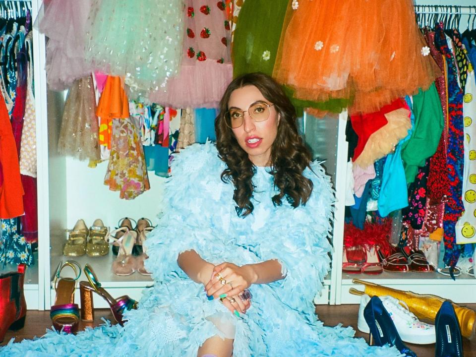 Caroline vazzana posing in front of the colorful clothing that fills her coveted closet