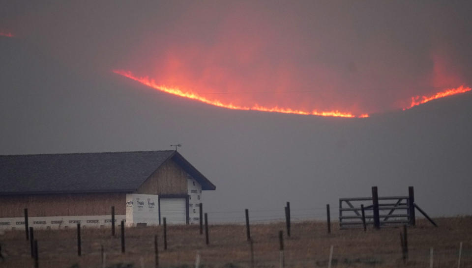 File—Flames rise from mountain ridges as a wildfire burns near a farmstead late Thursday, Oct. 22, 2020, near Granby, Colo. A bill is being introduced in the Colorado Legislature to create a $2-million pilot program to use cameras likely equipped with artificial intelligence technology in high-risk areas to help identify fires before they can burn out of control. (AP Photo/David Zalubowski, File)