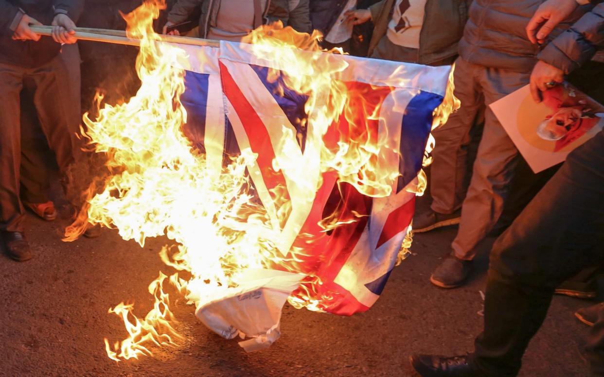 Iranian demonstrators set alight a Union Jack in front of the British embassy in Iran's capital Tehran - AFP