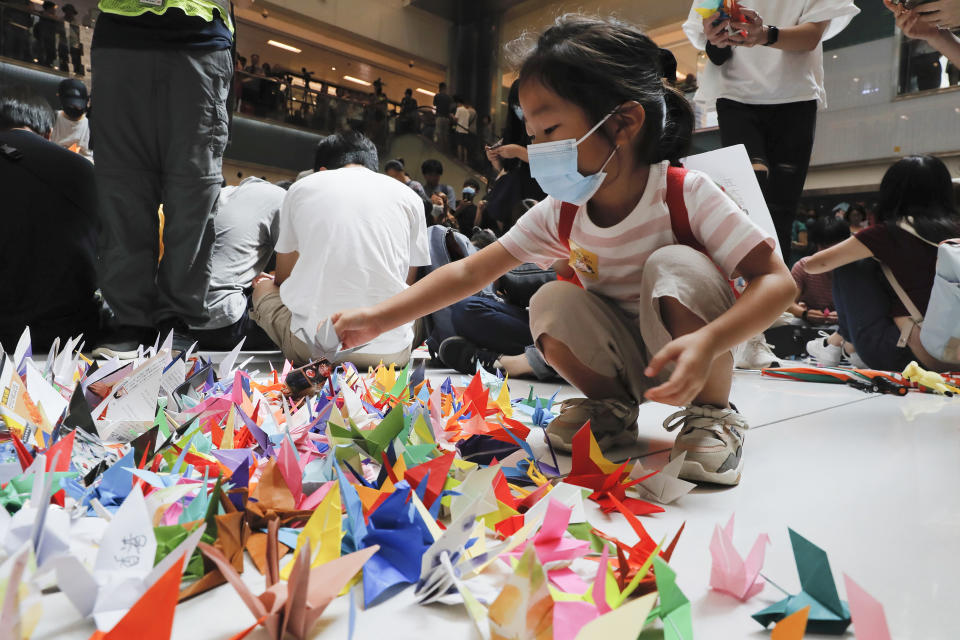 A child arranges origami cranes used in an anti-government rally inside a shopping mall at the Sha Tin district in Hong Kong, Sunday, Sept. 22, 2019. Young protesters, many wearing masks to disguise their identity, filled the open area of a Hong Kong shopping mall Sunday and folded paper "origami" cranes in the latest twist in a pro-democracy movement that has stretched into a fourth month. (AP Photo/Kin Cheung)