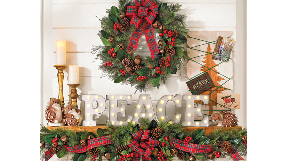 Christmas mantel ideas: Farmhouse chic mantel featuring a greenery garland and wreath kissed with berries and plaid ribbon, a marquee sign that spells 