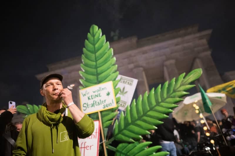 Thorsten smokes a joint during a "Smoke In" in front of the Brandenburg Gate. From 01 April 2024, adults aged 18 and over will be allowed to possess 25 grams of cannabis in public places. In private areas, up to 50 grams of home-grown cannabis will be permitted. Sebastian Gollnow/dpa