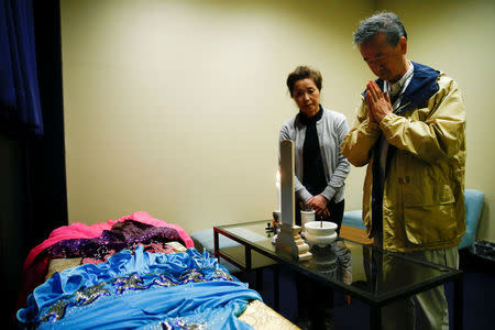 Customer Hirokazu Hosaka (R) prays to his mother as he stands at her coffin with his wife Minako Hosaka at the "Corpse Hotel" in Kawasaki, Japan, April 20, 2016. REUTERS/Thomas Peter