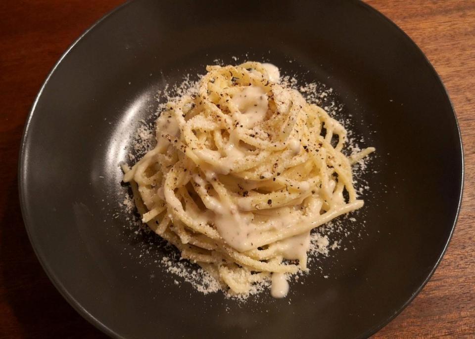 Cacio e pepe served in a pasta nest shape with extra pepper on top.