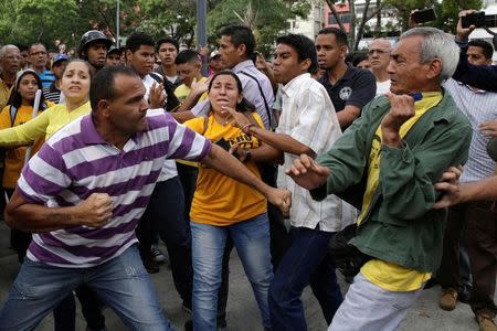 Partidarios del gobierno y opositores se enfrentan durante una protesta contra el presidente Nicolás Maduro fuera de la sede de la Fiscalía en Caracas. 31 de marzo de 2017. La fiscal general de Venezuela dijo el viernes, en una rara crítica, que la sentencia del máximo órgano judicial del país con la que se adjudicó competencias legislativas constituye una "ruptura del orden constitucional" y llamó a revisar la medida. REUTERS/Marco Bello