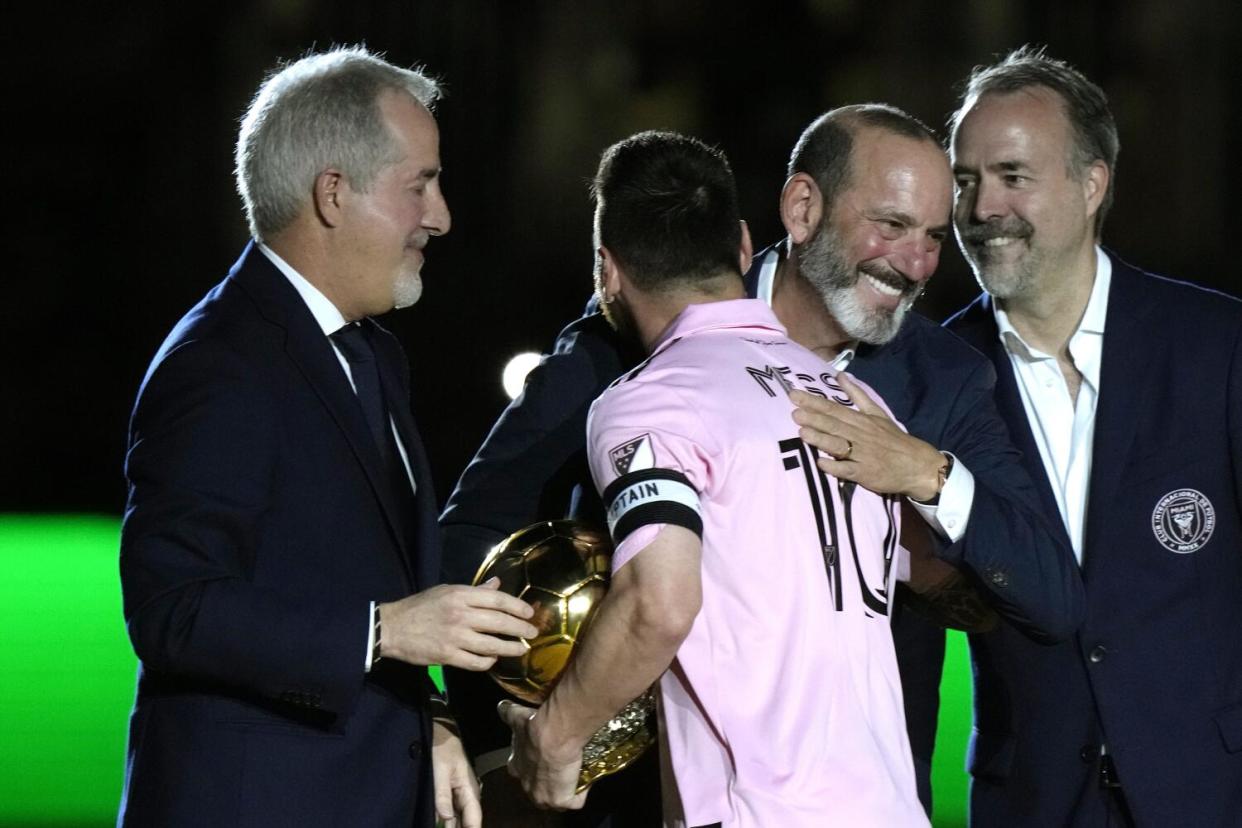 Inter Miami forward Lionel Messi is hugged by MLS commissioner Don Garber, center right.