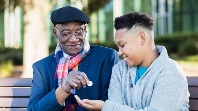 A 10 year old African-American boy sitting on a bench with his 79 year old great grandfather.