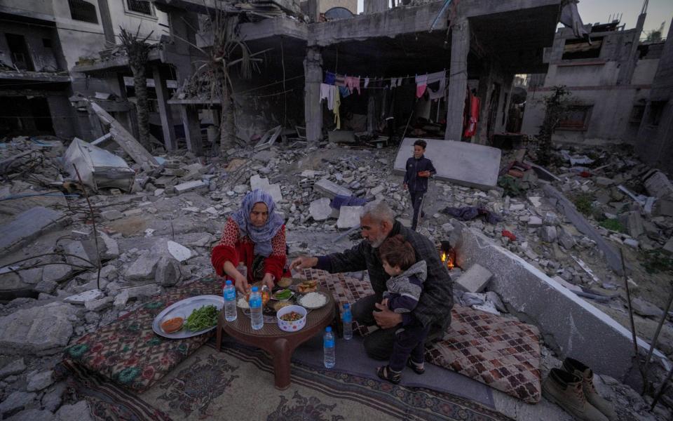 The Palestinian Al-Naji family prepare to break their fast during the first day of the Muslim holy fasting month of Ramadan sitting amidst the ruins of their family house in Deir el-Balah, central Gaza Strip, on March 11, 2024