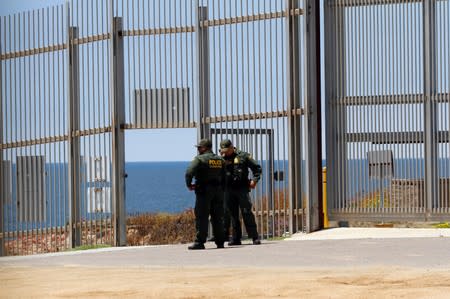 U.S. Border Patrol agent are seen in the border fence between the United States and Mexico as photographed from Tijuana