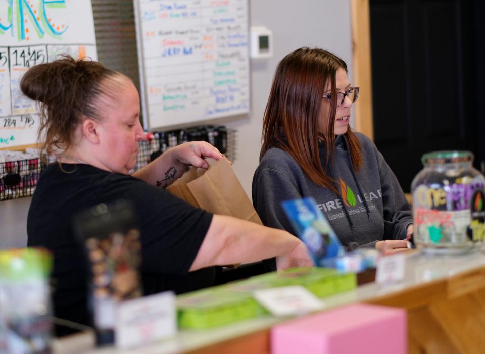 Tisha Bailey, left, and Kristen Poe check out a customer at the front counter at Fire Leaf Dispensary in Edmond.