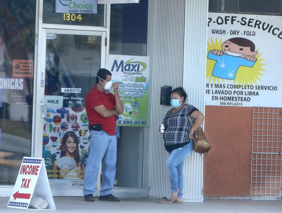 A couple wear protective masks due to the pandemic coronavirus Covid-19, as they stand in shopping mall located at Krome Avenue in Homestead on Tuesday. More cities are ordering people to wear masks when they go shopping or into other essential businesses.